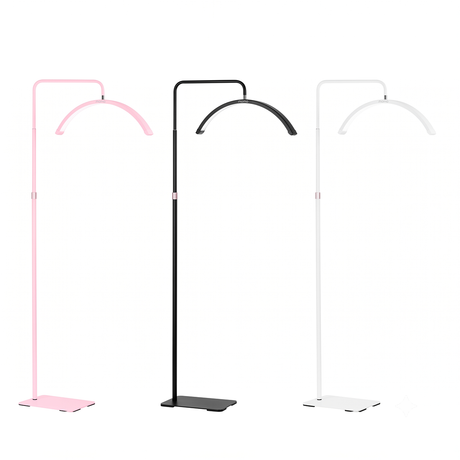 Three modern floor lamps with curved overhead arms and flat square bases, shown in pink, black, and white